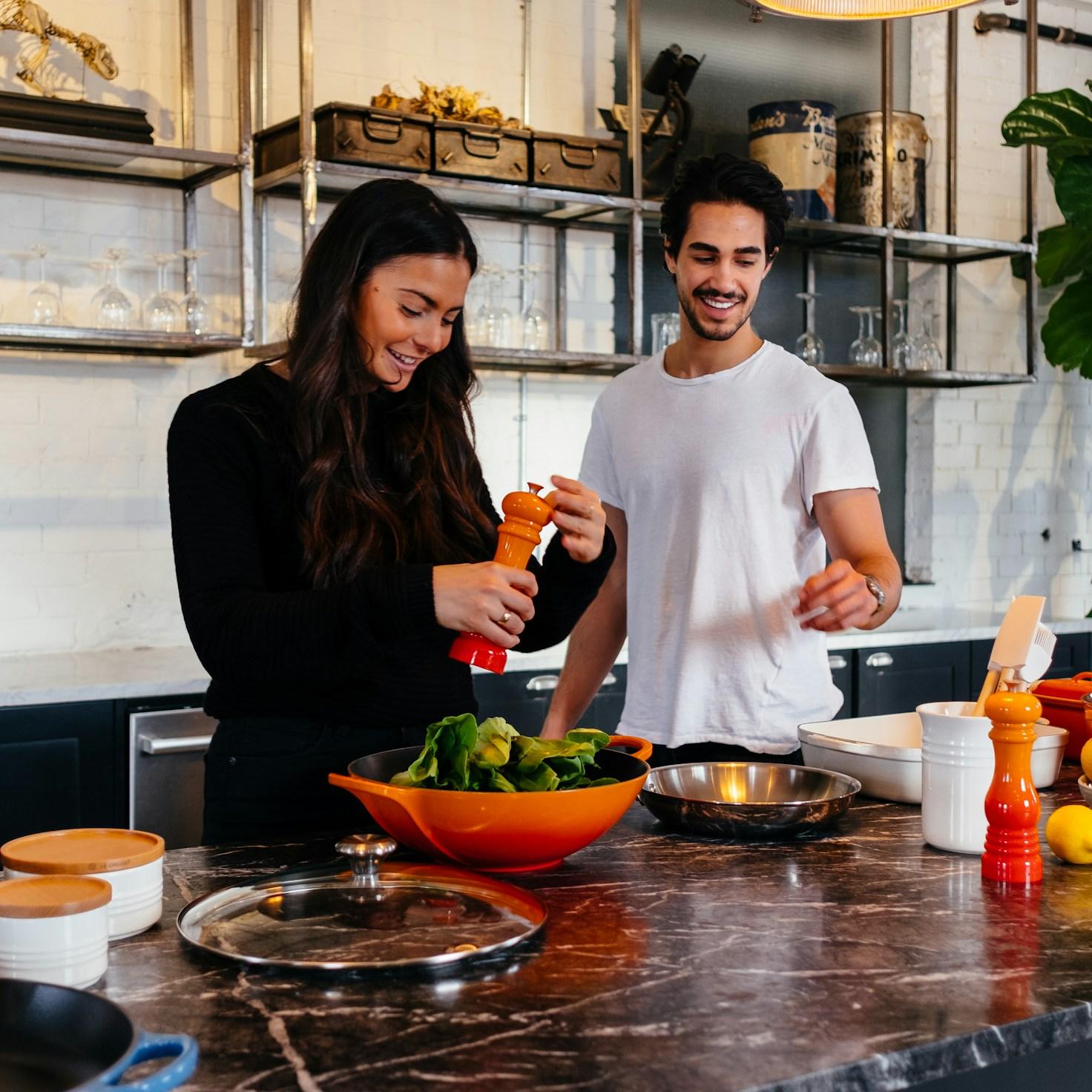 Friends collaborating in a contemporary kitchen, exchanging recipes and techniques
